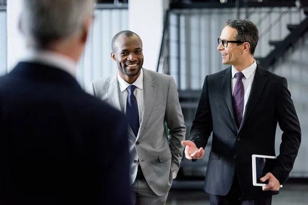 Foco Seletivo Homens Negócios Multirraciais Sorridentes Conversando Enquanto Caminham Escritório — Fotografia de Stock