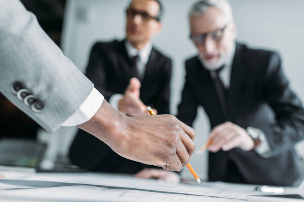 partial view of multicultural businessmen at meeting in office