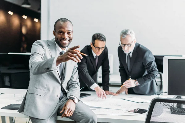 Smiling African American Businessman Pointing Away While Business Colleagues Discussing — Stock Photo, Image