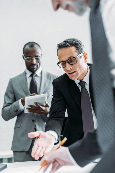 partial view of multicultural businessmen discussing new plan on meeting in office