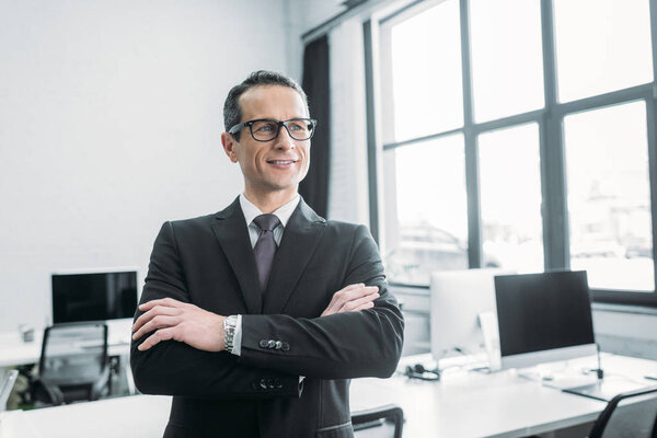 портрет улыбающегося бизнесмена со скрещенными руками
 