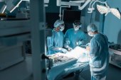 drei multikulturelle Chirurgen und Patienten im Operationssaal