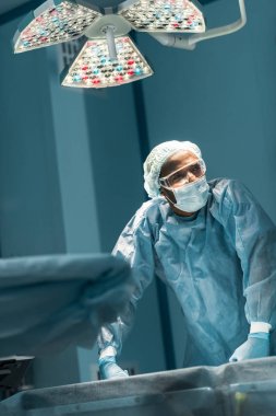 yorgun Afrikalı-Amerikalı cerrah ameliyat odasında uzağa arıyorsunuz
