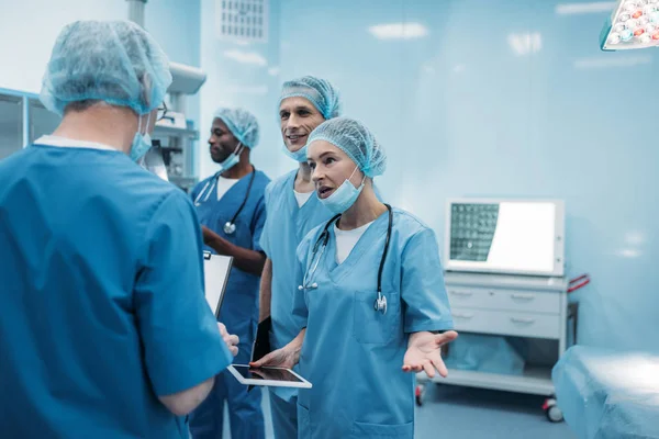 Четыре Мультиэтнических Хирурга Разговаривают Операционной — стоковое фото