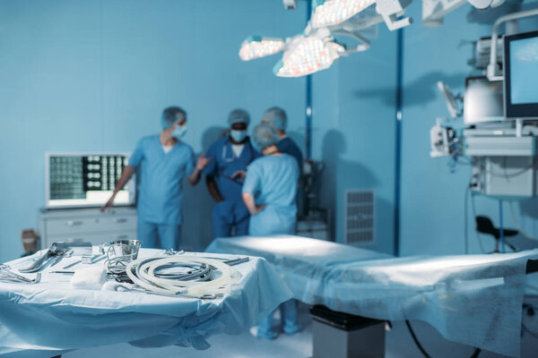 four multiethnic surgeons in operating room with tools on foreground