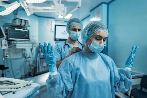 Médico Ajudando Usar Uniforme Cirúrgico Para Cirurgião — Fotos gratuitas