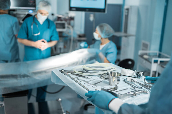 обрезанное изображение доктора, держащего поднос с медицинскими инструментами для хирургии
