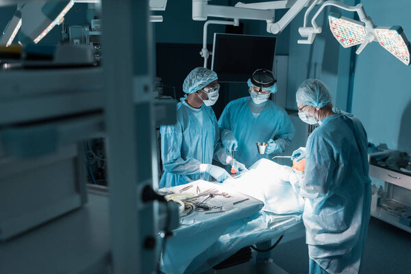 three multicultural surgeons and patient in operating room