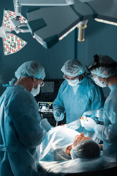 многонациональные хирурги, оперирующие пациента в операционной
