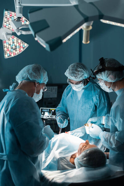 multiethnic surgeons operating patient in operating room