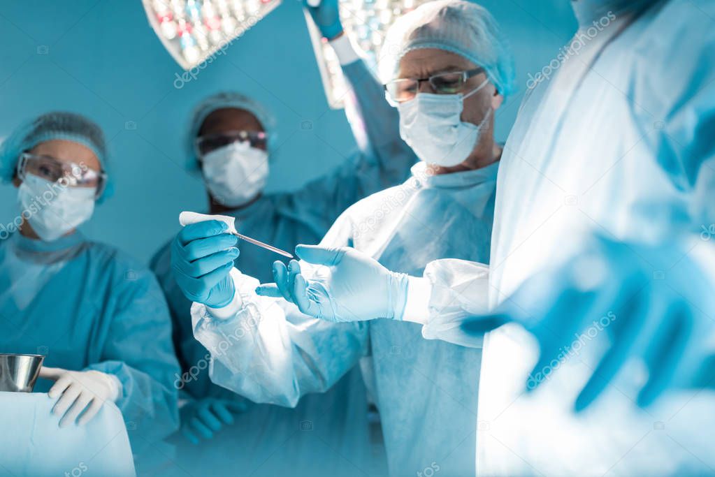 cropped image of doctor passing medical tool to surgeon