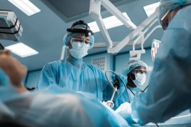multiethnic surgeons operating female patient clipart