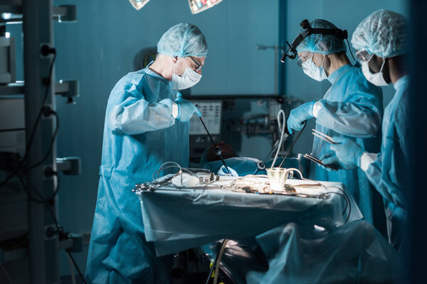 side view of multiethnic surgeons operating patient in operating room