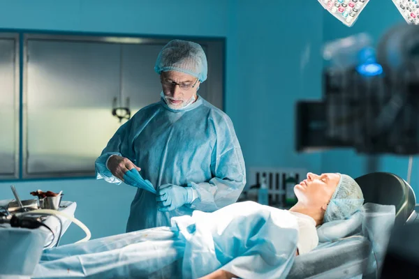 Médico Tirando Luvas Médicas Perto Paciente Sala Cirurgia — Fotografia de Stock