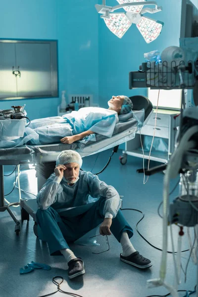 Orvos Ülő Földre Közelében Beteg Műtőasztalon — Stock Fotó