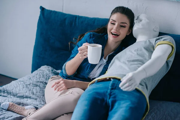 Jovem Com Xícara Café Falando Com Manequim Enquanto Descansa Cama — Fotografia de Stock