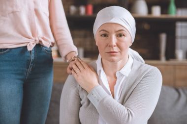cropped shot of woman supporting sick mature mother in kerchief looking at camera clipart