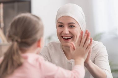 çocuk ve hasta anne elele ve birbirlerine gülümseyen atkı 