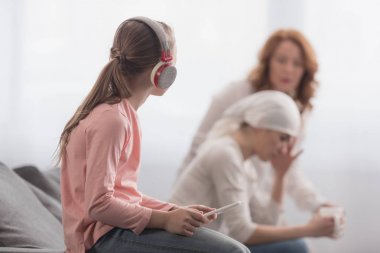 Çocuk dijital tablet kullanma ve hasta annem ve anneannem arkasında konuşan bakarak kulaklık  