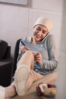 smartphone ile konuşmak ve notlar, kanser kavramı almak fuları gülümseyen genç kadın
