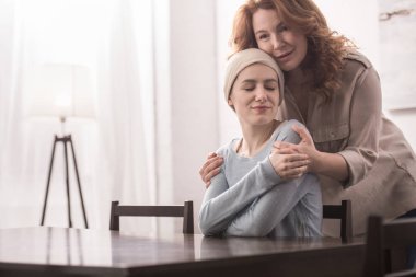 sarılma ve hasta gülümseyen kızı fular destekleyen olgun kadın