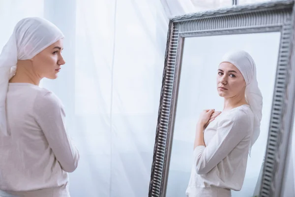 Νεαρή Άρρωστη Γυναίκα Στο Μαντήλι Κοιτάζοντας Καθρέφτη Έννοια Του Καρκίνου — Φωτογραφία Αρχείου
