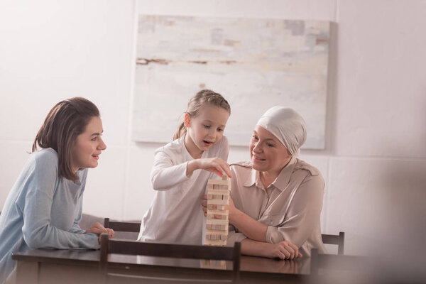 happy family of three generations playing with wooden blocks together, cancer concept 