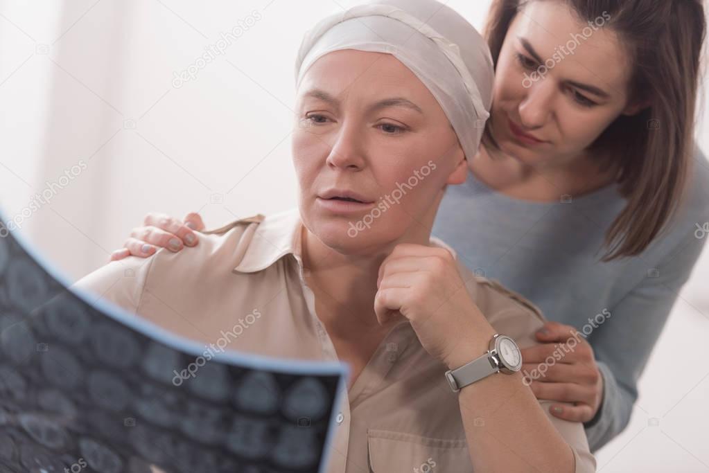 woman supporting sick mature mother holding mri scan 