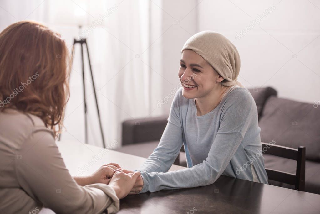 mother and sick adult daughter in kerchief holding hands and looking at each other