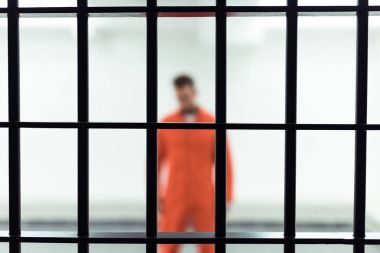 prisoner in prison cell with metallic bars on foreground  clipart