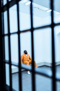 Afro-Amerikan mahkûm hapishane hücresinde bankta oturmuş