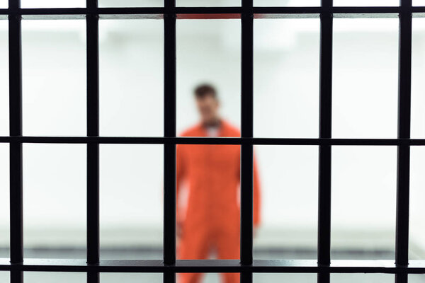 prisoner in prison cell with metallic bars on foreground 