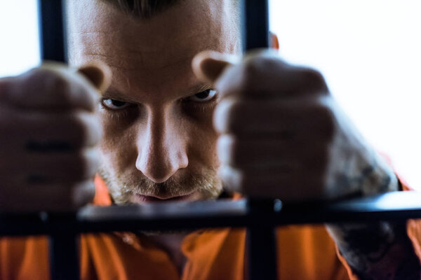 aggressive prisoner holding prison bars and looking at camera