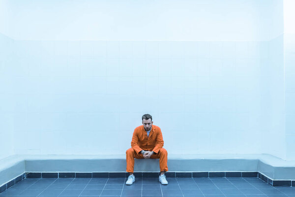 prisoner sitting on bench in prison room