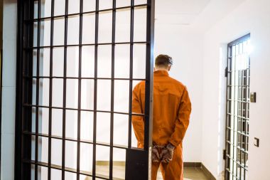 back view of prisoner standing in handcuffs in corridor clipart