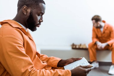 side view of african american prisoner reading book clipart