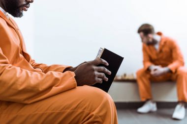 cropped image of african american prisoner reading book clipart