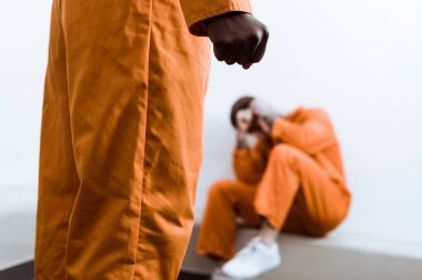 cropped image of african american prisoner standing with fist on foreground clipart