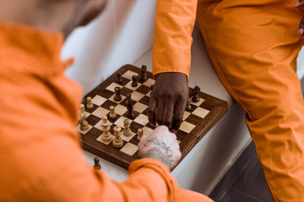 обрезанный образ мультикультурных заключенных, играющих в шахматы
