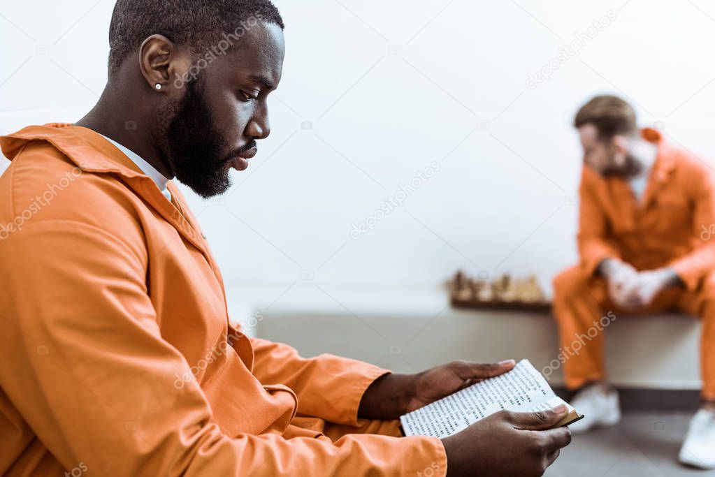 side view of african american prisoner reading book
