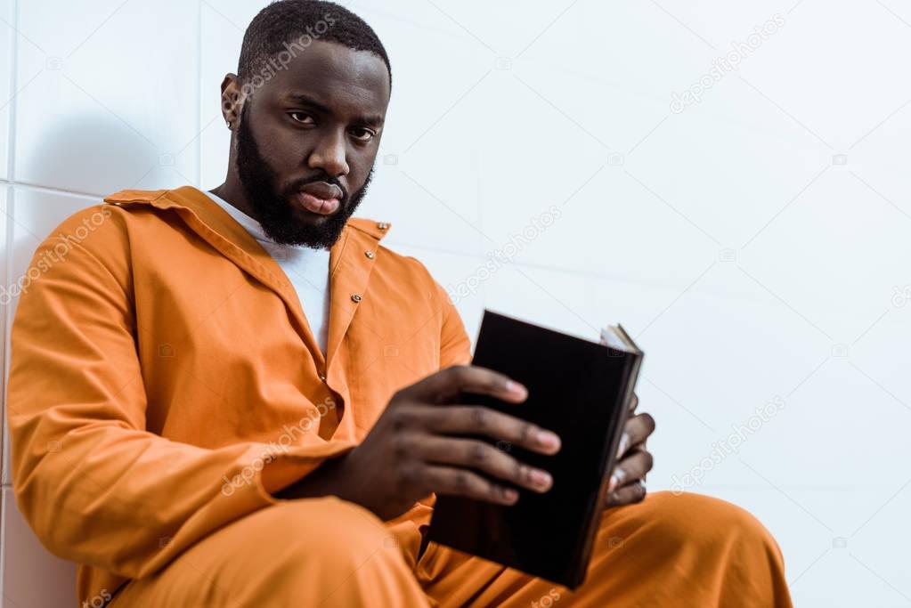 african american prisoner holding book and looking at camera
