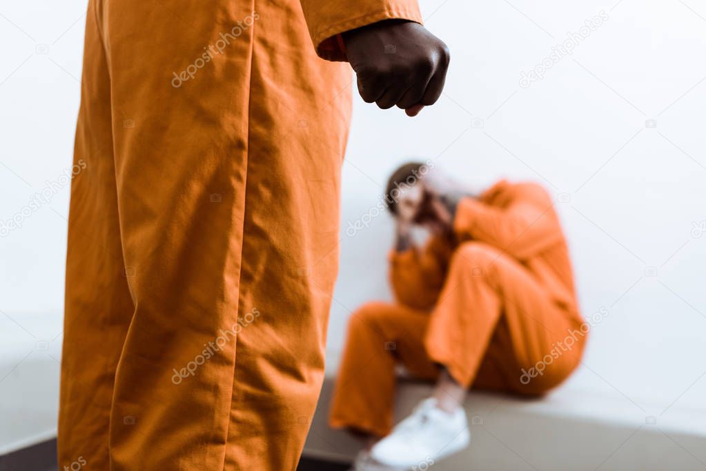 cropped image of african american prisoner standing with fist on foreground