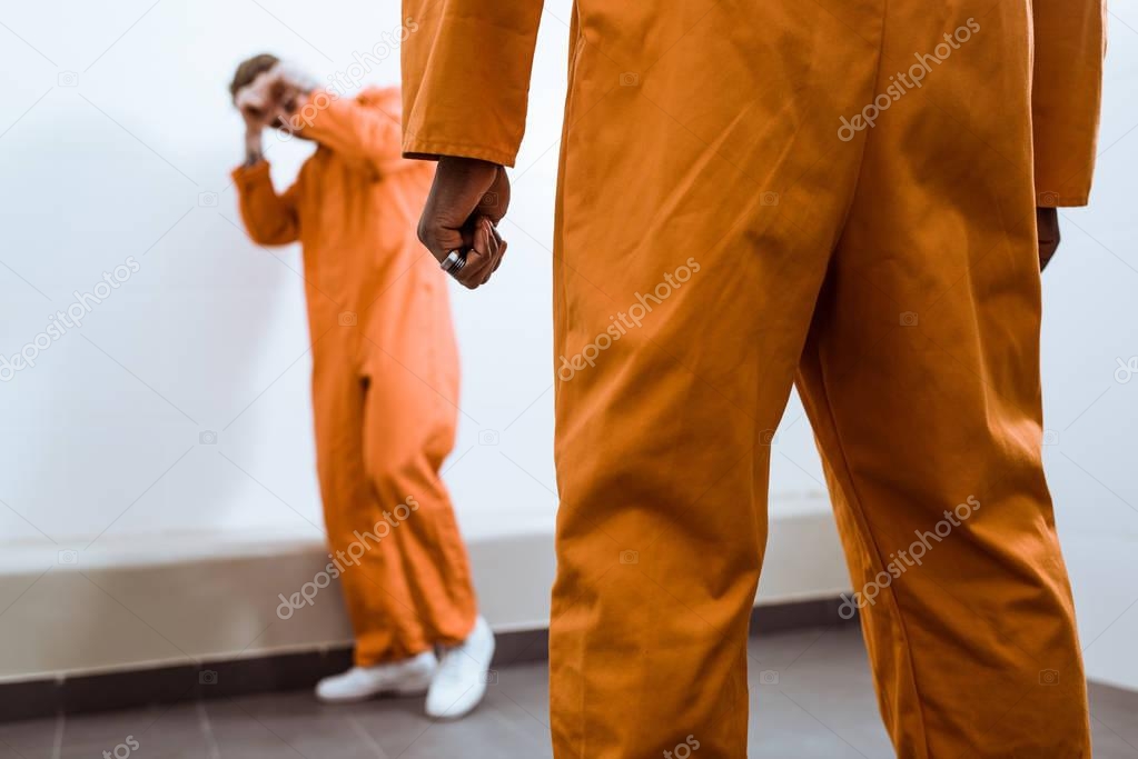 cropped image of multicultural prisoners fighting in prison cell