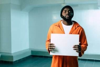 african american prisoner holding blank placard and looking at camera clipart