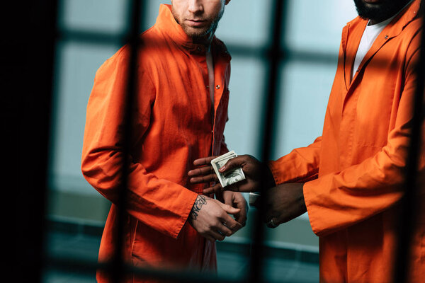 обрезанное изображение заключенного, покупающего наркотики у африканского американского заключенного в тюремной камере
