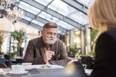 Kısmi görünümü üst düzey erkek ve kadın birlikte restoranda akşam yemeği