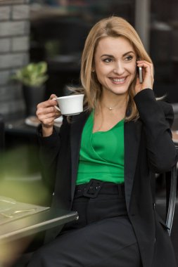 gülümseyen kadın portresi ile smartphone kafede konuşurken kahve