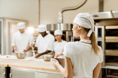 arka planda çalışan bulanık meslektaşları ile arkadan görünüşü işyerinde genç kadın baker
