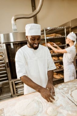 Afro-Amerikan baker arka plan üzerinde bulanık üretim çalışma meslektaşı süre pişirme, hamur yoğurma