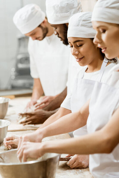 group of multiethnic bakers kneading dough together